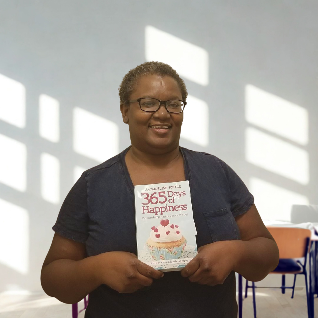 Person holding a book titled '365 Days of Happiness' in a bright room with sunlight filtering through.